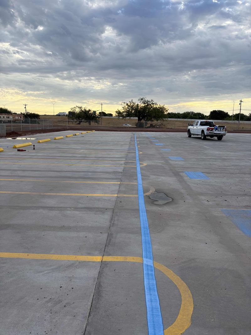 Concrete paving and fresh blue and yellow parking lot striping by Circle H Civil on a truck lot