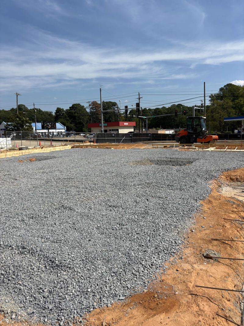 Leveled crushed-stone building pad on a red-dirt commercial site