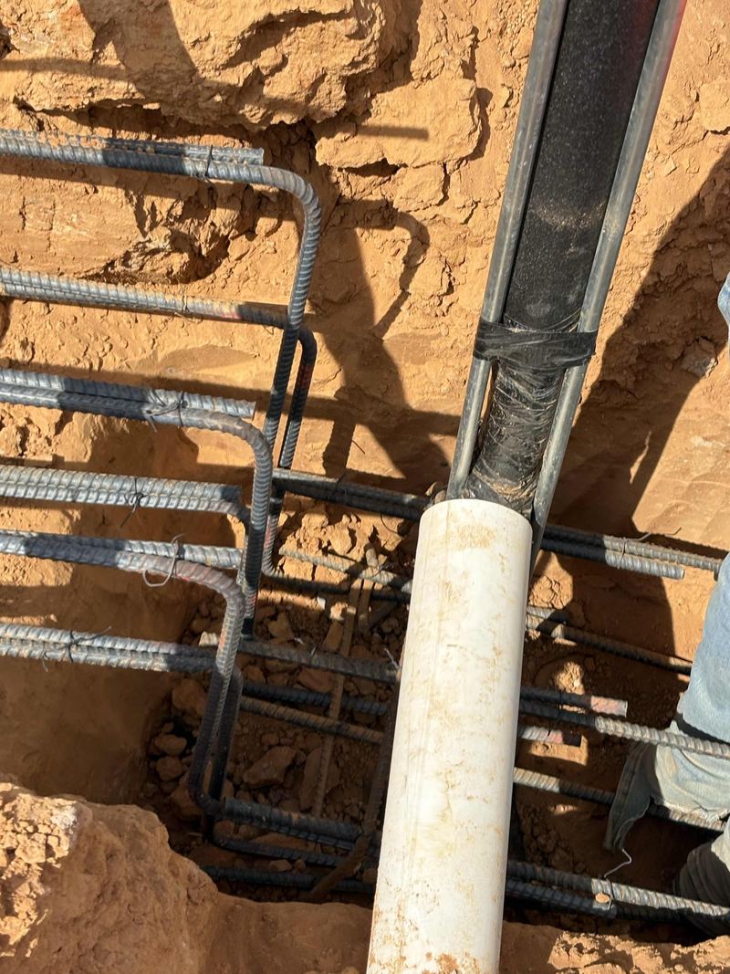 Rebar cage and PVC pipe set in an excavated footing hole