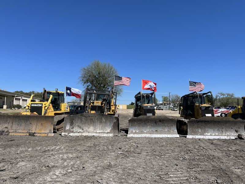 Row of Circle H dozers lined up with American and Texas flags flying